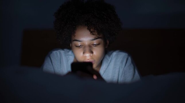 African American teen in puberty with Afro hairstyle is chatting at night. Generation Z: a zoomer is always online