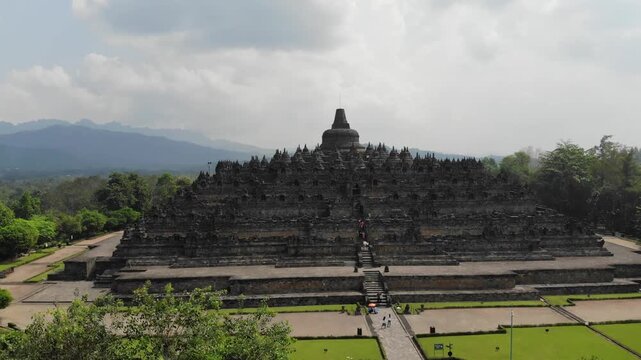 Cinematic Aerial Spiral Orbit Approaching Borobudur Temple - 4K. The drone performs a complex spiral maneuver, combining a dolly in (push in) movement with a smooth orbit
