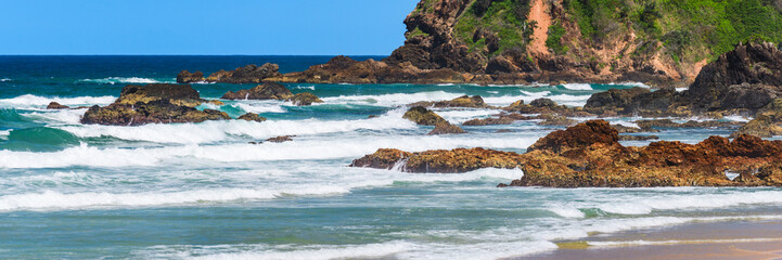 Australian coast, big rock on the seashore surrounded by the sea with big waves, view from the beach to the seaside landscape on a summer sunny day.
