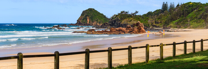 Australian coast, big rock on the seashore surrounded by the sea with big waves, view from the beach to the seaside landscape on a summer sunny day.