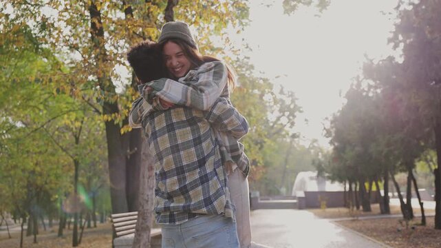 Young couple two friends family man woman wear casual clothes together boy hold girl in arms turn around spin walk rest relax in fall city park go down alley outdoors on nature. Urban leisure concept