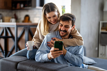 Happy couple using smartphone for social media mobile banking and modern digital lifestyle together