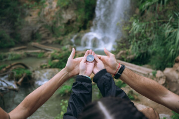 Group hands holding compass finding direction in nature
