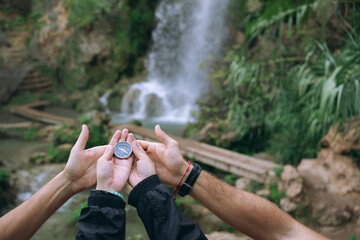 Team hands holding compass showing direction outdoor adventure