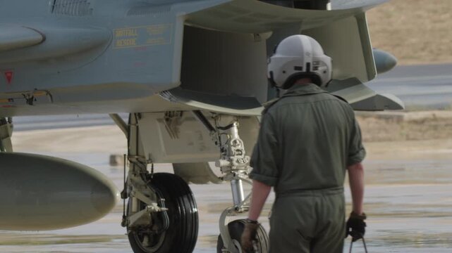 Military ground crew approaching fighter jet on runway during post flight inspection and maintenance procedure