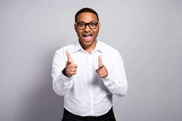 Young handsome businessman in white shirt smiles and points at the camera in a confident office...