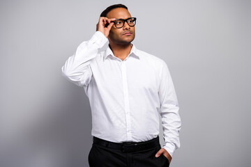 Young handsome businessman in white shirt and glasses stands in a professional office looking...