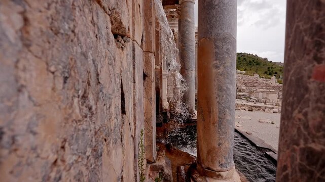 Flowing water cascading among stone walls and Roman columns in Sagalassos Ancient City, Burdur, Turkey. Ancient architecture, cultural heritage, archaeology, and historic atmosphere concept.