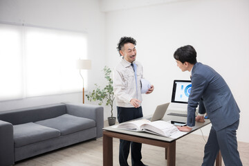 作業着の男性とスーツの男性が施工など打ち合わせをする