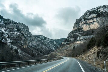 Winding mountain road through a snowy winter canyon on a cloudy day