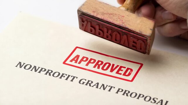 Brainstorming nonprofit grant proposal document with hand stamped paper for funding approval supporting charitable projects and community initiatives