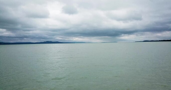 Aerial view of the expansive Lake Balaton under a dramatic overcast sky, the water reflecting the muted tones of the cloudscape, Fonyod, Hungary.