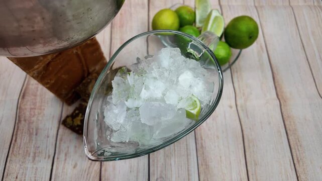 Pouring golden panela syrup into pitcher with ice and lime for drink