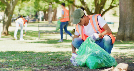 Volunteer, cleaning and man in park with plastic bag to collect trash, garbage and litter for...