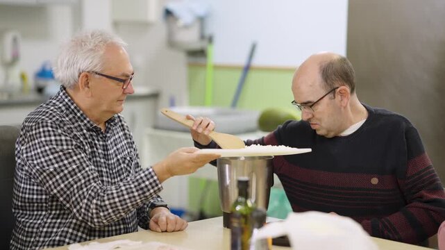 Man with a disability learning to cook in a social inclusion workshop. An educator assists him in preparing a meal, promoting daily living skills