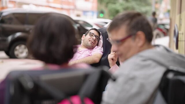 Group of three happy friends with disabilities sitting in wheelchairs on a city street. Individuals enjoying a cheerful conversation and social interaction