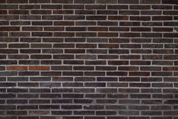 Obraz premium Ancient black brick wall featuring aged bricks, cracks and distressed texture. Monochrome architectural background with gritty and rustic appearance.