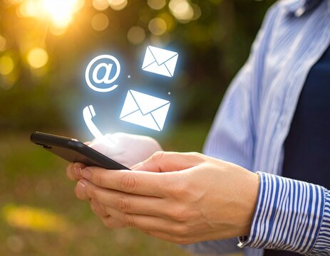 Person holding a smartphone with glowing digital communication icons floating above it, representing connectivity and contact.