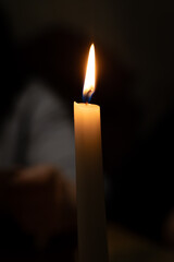 Close-up of a lit candle against a dark, blurred background, creating a warm and serene atmosphere suitable for various themes and designs.