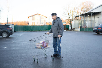 Senior male handling grocery cart on urban parking area, daily routine activity, independent lifestyle in public space
