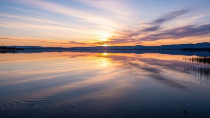 Serene sunset over tranquil lake with vibrant sky reflections and distant mountains creating a
