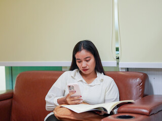 Candid business people using smartphone collaborative spaces sitting sofa workplace. Businesswoman co working remote work AI chatbot in office. Female leadership use technology. Business casual 