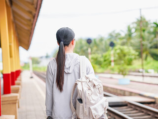 Asian woman suitcase walking at railroad station alone in holiday background. Tourist Female with luggage waiting train at terminal railway. People planning backpacks 