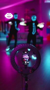 Cyber neon dancers performing virtual idol style dance filmed on phone digital avatar performance futuristic creator economy fan cam culture