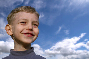 Happy smiling boy with a blue sky background.