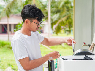 Asian man checking fertilizer vegetable hydroponics at home. People small business food farm. Healthy lifestyle crop ecology eco friendly for plantation and nutrition.