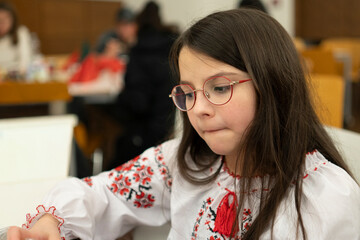 Pensive schoolgirl in glasses sitting in classroom, loneliness and emotions concept