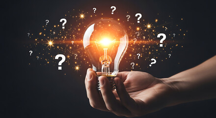 Hand holding glowing lightbulb amid question marks, idea and innovation