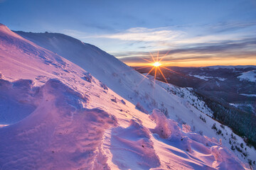 View of the sun rising over the snow-covered mountain peaks, casting a pink and purple hue on the landscape, Velka Chochula, Zilinsky kraj, Slovakia.