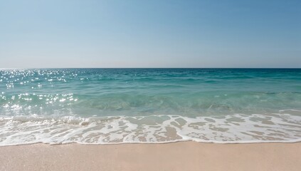 Fototapeta premium A serene ocean view with crystal clear turquoise water washing over the sandy shore under a bright blue sky. A perfect depiction of a tranquil paradise