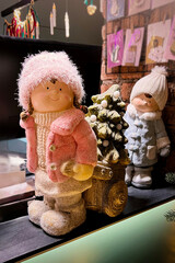 Holiday decor with dolls in winter outfits, Christmas tree, and sleigh at flower shop. Christmas...