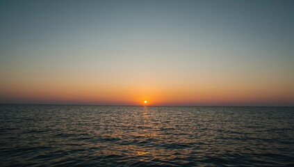 The setting sun casting a warm glow over the tranquil ocean, creating a serene and captivating scene. The colors of the sky blend seamlessly with the water, painting a picturesque panorama