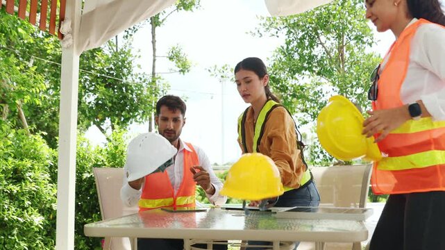 Indoor meeting male and female engineers discusses plans for a wind turbine system inspection renewable energy and sustainability before fieldwork : Renewable energy concepts that rely on wind.