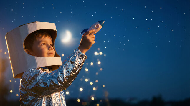 Childhood dreams of space: Young boy in a handmade astronaut costume holds a toy rocket under a beautiful starry night sky.