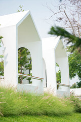 Modern White Minimalist Pavilion Architecture on Green Hill with Grass Flowers