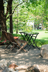 Wooden Chairs and Glass Tables in Shady Garden with Dappled Sunlight
