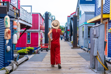 Tourist walking on fisherman's wharf park boardwalk in victoria, british columbia