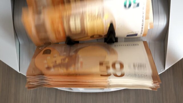 Counting machine processes fifty Euro banknotes quickly on a table the machine efficiently sorts cash