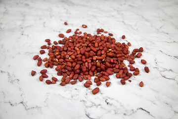 A pile of brown peanuts on a white marble table. Food is healthy agricultural products.
