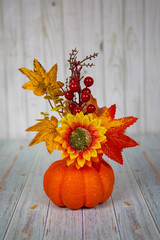 Pumpkin with sunflower flower, maple leaves and red cherry on a wooden table. Food, vegetables, agriculture, healthy foods.