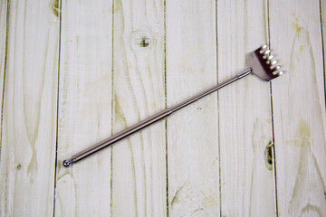 A metal stick with a toothed comb or a back scratcher isolated on a white background. Tools, household items, medicine.