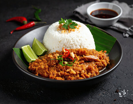 A delicious plate of nasi dagang with ikan aya, a flavorful Southeast Asian dish served with lime wedges and chili, expertly prepared and presented.