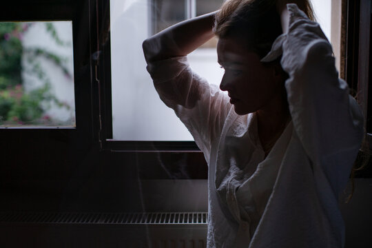 Woman silhouetted against window in dim light