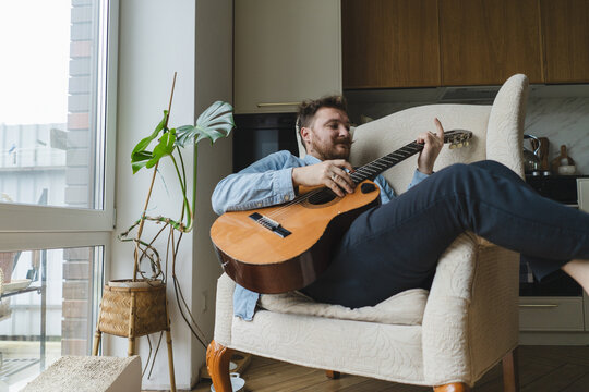 Young man enjoying guitar music at home
