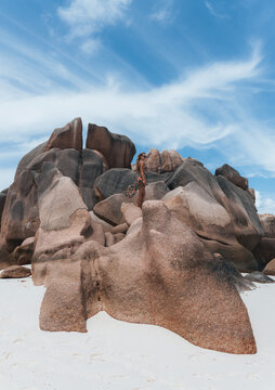 Woman standing on rocks at Anse Cocos, La Digue