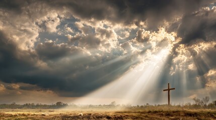 A Cross silhouetted against a dramatic cloudy sky with sun rays shining through. An image of hope and faith. 